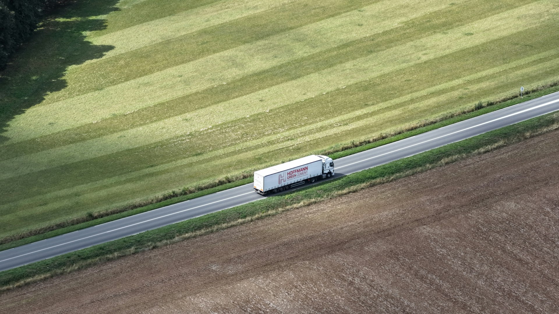 White truck driving on a road through fields